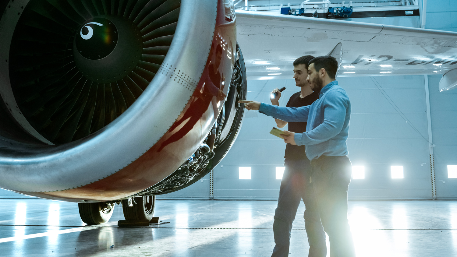 Two maintenance people work on an aircraft engine