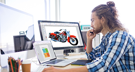 Image of a person creating a graphic design project on a desktop computer using two screens and using Canvas graphic design software. | Canvas GFX