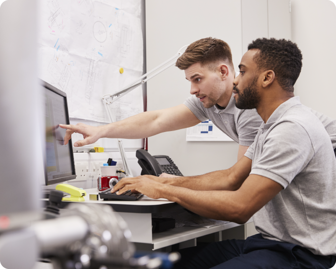 Two people work on a technical document at a computer